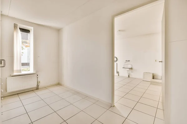 an empty room with white tile flooring and large open door leading to the bathroom area in this apartment building