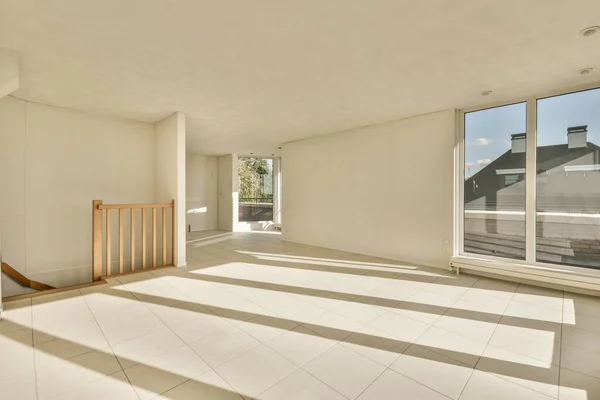 an empty living room with white tile flooring and large windows looking out onto the street in front of the house