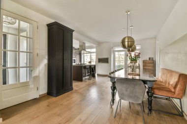 Çağdaş dairenin geniş odasında dinlenme odası ve mutfağı olan sandalyeli bir masa.