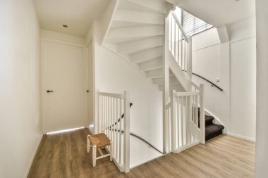 Dar merdivenlerin yukarısından, beyaz merdivenler ve modern dairenin duvarlarında parmaklıklar.