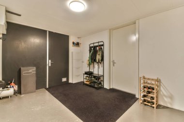 Beyaz duvarlı geniş bir odada birçok kapısı ve mühendislik iletişimi olan bir koridor.