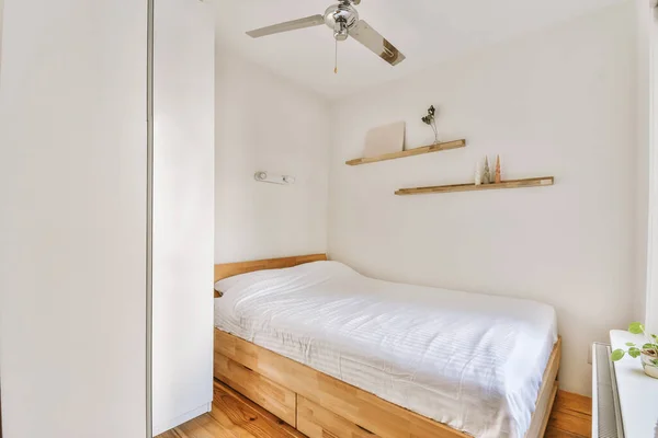 a bedroom with a bed and ceiling fan on the wall in front of the bed is an open door that leads to another room