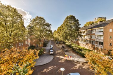 Sokakta arabaların park ettiği ve arka planda evlerin olduğu bir yerleşim yeri. Hava aracı kamerasından alınmış.