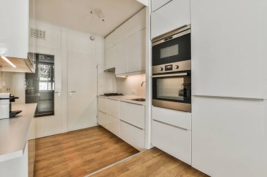 Çağdaş dairenin geniş odasındaki dinlenme odası ve mutfağın yanındaki sandalyeli masa.