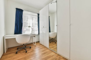 Beyaz masalı ve pencereli gardırobu olan aydınlık ev ofisinin içinde.