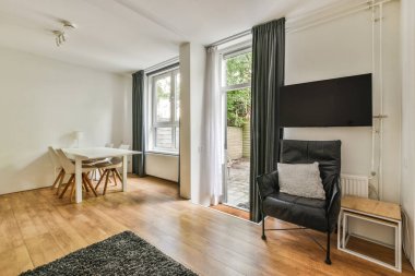 Çağdaş dairenin geniş odasındaki dinlenme odası ve mutfağın yanındaki sandalyeli masa.