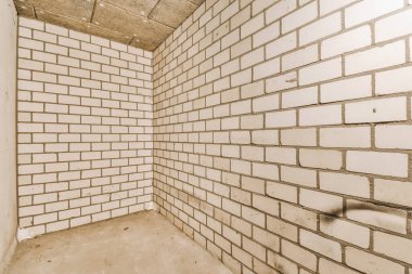 Duvarlarında beyaz tuğlalar olan ve tuvaletin olmadığı yerde döşemeler olan bir odanın içinde.