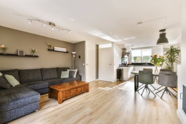 Odanın ortasında ahşap döşemeli ve gri koltuklu bir oturma odası yemek masası.