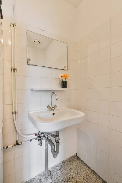 a white bathroom with black and white mosaic tiles on the floor, sink and mirror in the shower stall area