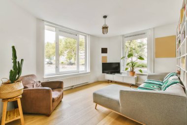 Oturma odası, iki kanepe ve bir sehpa büyük bir pencerenin önünde sokağa bakıyor.