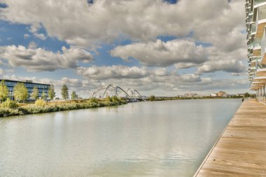 Diğer tarafında binalar ve üzerinde bulutlar olan bir nehir. Suyun karşısından görüldüğü gibi.