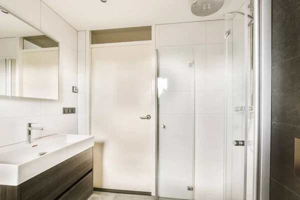 a modern bathroom with white walls and dark wood vanity, shower stall and sink in the room is very clean