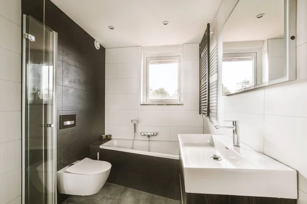 a modern bathroom with black and white tiles on the walls, along with a walk - in shower stall next to the toilet
