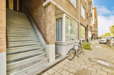 Kaldırımdaki bir binanın önüne park edilmiş bir bisiklet merdivenlerin yanına park edilmiş merdivenler ve yakınındaki arabaların olduğu basamaklar.