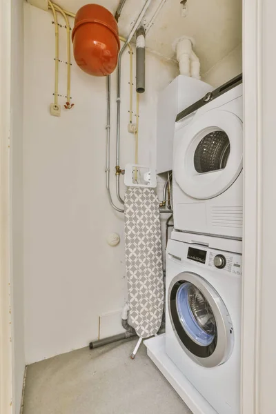 a laundry room with a washer and dryer next to the door that leads to an open bathroom area