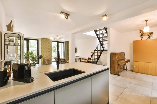 a kitchen and living room in a house with stairs leading up to the second floor, there is an open staircase