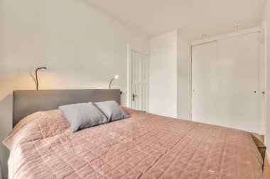 Yatak odasının içi parlak renklerde ve parke zemininde beyaz bir gardırop var.