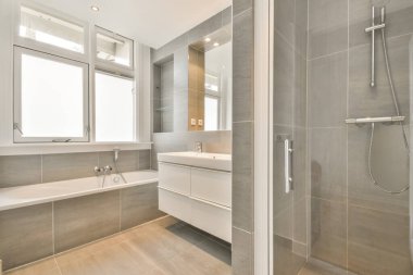 Seramik küveti, lavabosu ve duşu olan gri dizaynlı banyo.