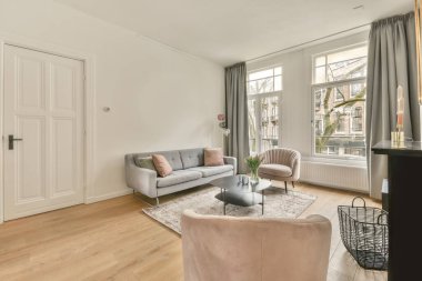 Geniş bir oturma odasının içi. Açık bir tasarım. Rahat bir evde büyük bir kanepe ve halı var.