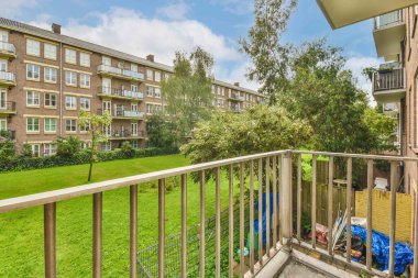 Panoramic view of brick buildings with parking and trees from small balcony