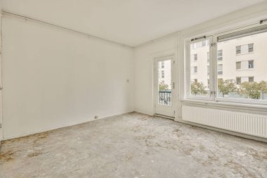 Evdeki boş ışık odasında, beyaz duvardaki plastik pencere ve radyatör.