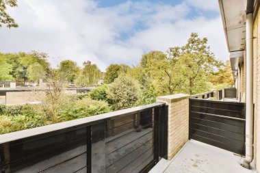 Uzakta ağaçlar ve çalılar olan bir dış alan. Buna yıllardır kullanılan siyah bir çit de dahil.