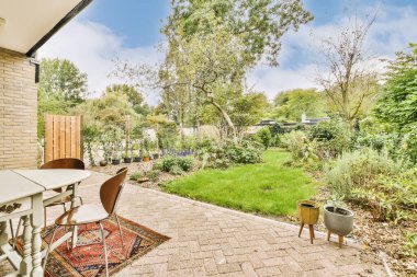 Evin önündeki avluda bir masa, sandalyeler ve açık hava yemek seti.