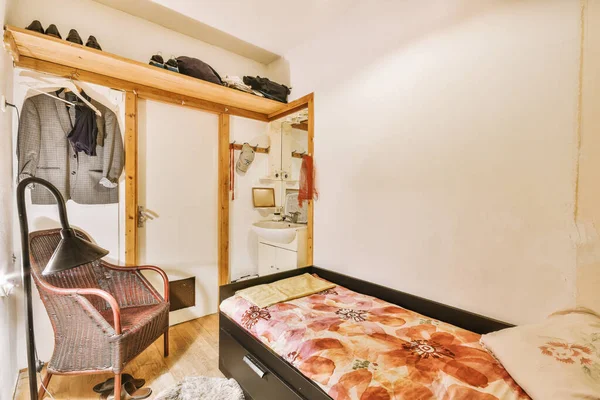 a bedroom with a bed, chair and clothes hanging on the wall in front of the door to the room