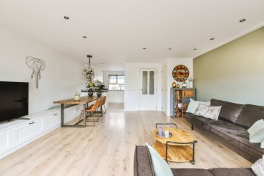 Ahşap döşemeleri ve yeşil duvarları olan bir oturma odası. Duvara monte edilmiş büyük bir düz ekran televizyon da dahil.