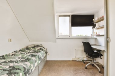 Yanındaki duvarda yatağı, masası ve bilgisayarı olan bir oda dışarıdan bakan bir penceredir.