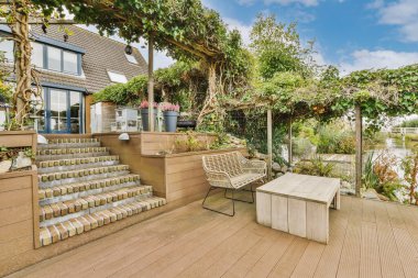 Yan tarafında bir sürü bitki olan bir teras ve üst kata çıkan merdivenler var. Açık bir oturma alanı var.