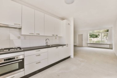 Bu odadaki tezgahların üzerinde beyaz dolaplar ve siyah tezgahlar olan bir mutfak çok temiz, ama öyle değil.