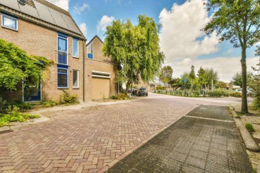 Parlak güneşli bir günde arka planda ağaçlar ve evler olan tuğlalı bir cadde, Hollanda stok fotoğrafı - haklar