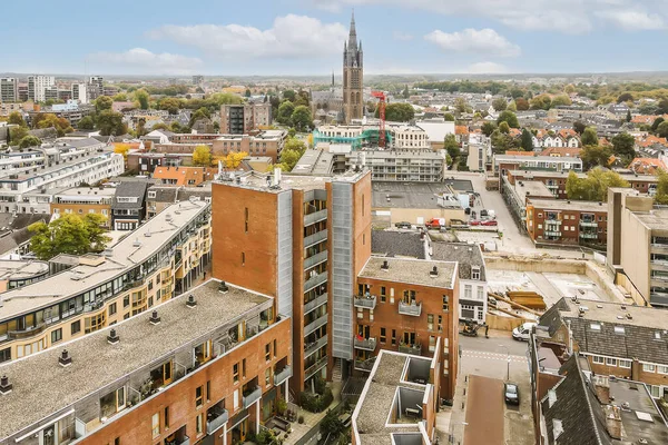 Uzakta saat kulesi ve her iki tarafında binaları olan yüksek bir binanın tepesinden bir şehir.