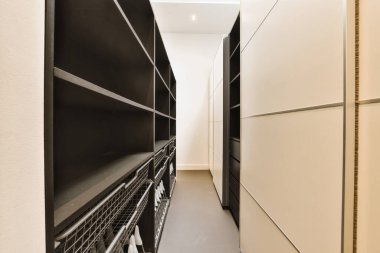 Her iki tarafında siyah beyaz dolaplar olan uzun, dar bir koridor, bizi başka bir odaya götürecek açık bir kapıya götürüyor.