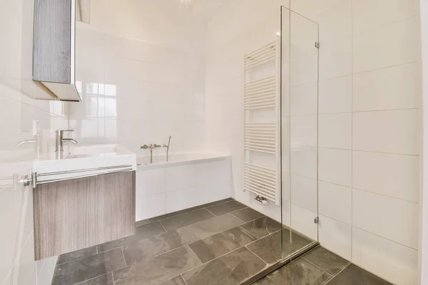 a bathroom with tile flooring and white tiles on the walls, along with a shower stall in the corner