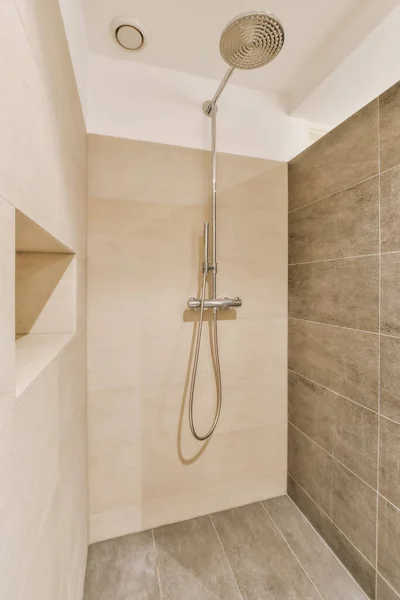 a shower in a bathroom with tiled walls and tile flooring on the wall, there is a hand held shower head