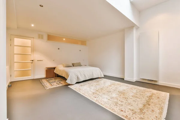 a bedroom with an area rug on the floor and a bed in the corner between the door to the room