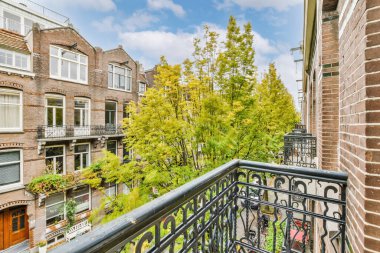 Arka planda ağaçlar ve binalar olan bir apartman balkonunda, Amsterdam, Hollanda stok fotoğrafı - premium telif faizi