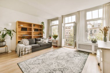 Ahşap döşemeli ve geniş pencereli bir oturma odası. Şehir manzaralı odalara bakıyor.