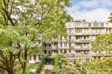 Ön planda ağaçlar ve çalılar olan bir apartman kompleksi, güneşli bir günde yukarıdan alındı.