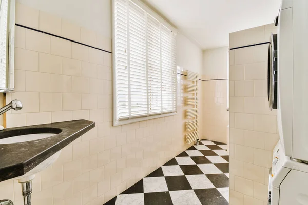 a bathroom with black and white checkered tiles on the floor, along with a toilet in the corner next to the window