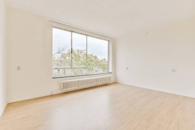 Ahşap zemini ve beyaz duvarları olan boş bir oda. Sokağa bakan büyük bir pencere var.