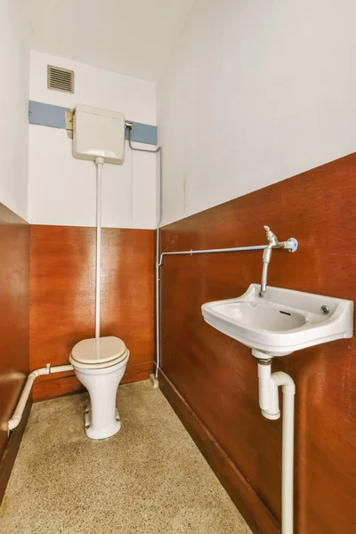 a toilet and sink in a small bathroom with wood paneling on the walls behind it is a wall mounted air condition