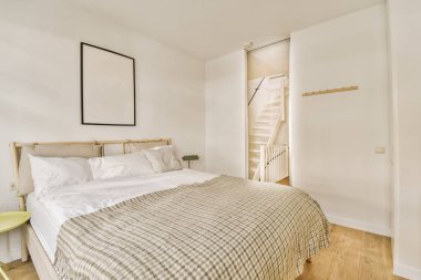 Duvarında yatak odası, sandalye ve ayna olan bir yatak odası. Merdivenlere açılan açık bir kapının yanında.