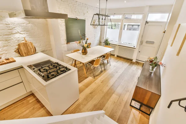 a kitchen and dining area in a small apartment with white walls, wood flooring and an oven on the stove