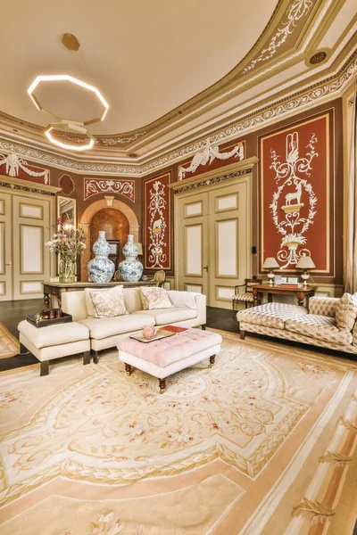 a living room with red and white wallpapers on the walls, an area rug is in the center of the room