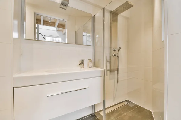 a modern bathroom with white walls and tile flooring, along with a shower stall in the room has a mirror on the wall