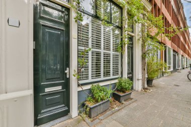 Üzerinde bitkiler büyüyen bir bina ve sağdaki kapının önüne park edilmiş bir bisiklet.