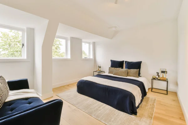 a bedroom with white walls and hardwood flooring in the room, there is a bed that has blue comforter on it